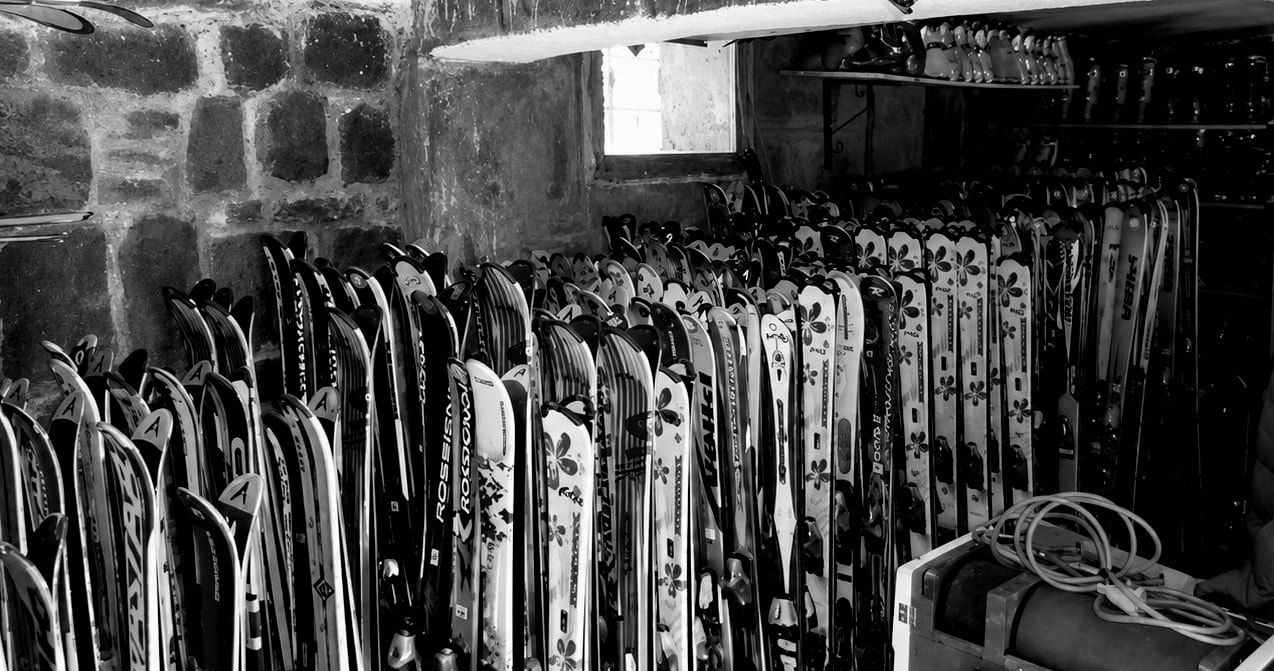 Intérieur du magasin Univers Glisse : les racks de skis de location alignés le long des murs en pierre